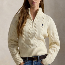 Model wearing Polo Ralph Lauren Authentic Cream cable-knit half-zip jumper with navy pony logo, styled with blue jeans and brown belt.