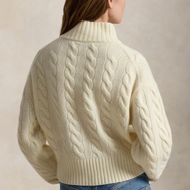 Model wearing Polo Ralph Lauren Authentic Cream cable-knit turtleneck sweater with voluminous sleeves, styled with blue jeans.
