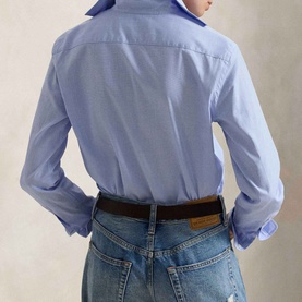 Model wearing a light blue long-sleeve button shirt, styled with blue jeans and a brown leather belt, rear view