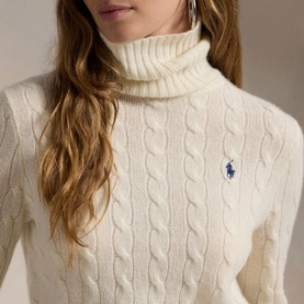 Model wearing Polo Ralph Lauren Authentic Cream cable-knit turtleneck sweater with navy embroidered pony logo detail.