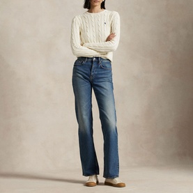 Model wearing Polo Ralph Lauren Authentic Cream cable-knit sweater with blue bootcut jeans and gold loafers.