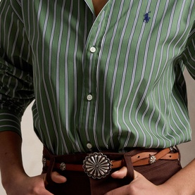 Model wearing Polo Ralph Lauren green and white striped shirt with navy logo, styled with a brown leather belt with silver concho buckle.