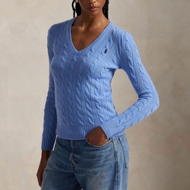 Model wearing blue cable-knit V-neck sweater with embroidered pony logo, styled with blue jeans