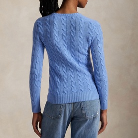 Model wearing a blue cable-knit crew-neck sweater, styled with light-wash jeans, seen from behind