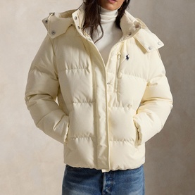 Model wearing Polo Ralph Lauren Estate Cream puffer coat with detachable hood, styled with white roll-neck and blue jeans.