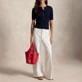 Model wearing Polo Ralph Lauren Hunter Navy short-sleeve ribbed knit top, styled with white wide-leg trousers and red tote bag.