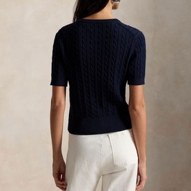 Model wearing Polo Ralph Lauren Hunter Navy cable-knit short-sleeve sweater, back view, styled with white wide-leg trousers.