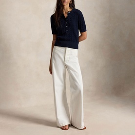 Model wearing Polo Ralph Lauren Hunter Navy short-sleeve ribbed knit polo, styled with wide-leg white trousers.