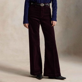 Model wearing Polo Ralph Lauren Midnight Merlot wide-leg corduroy trousers, styled with a blue knit and western belt buckle.