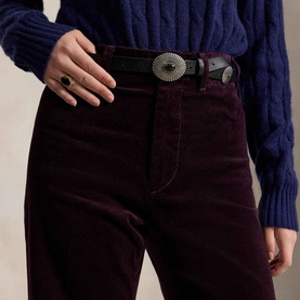 Model wearing Polo Ralph Lauren Midnight Merlot corduroy trousers, styled with a navy cable-knit sweater and black western belt with silver hardware.