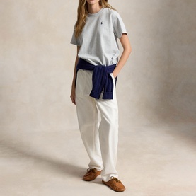Model wearing Polo Ralph Lauren Grey Ash Heather T-Shirt with white trousers and navy jumper tied at waist, brown loafers