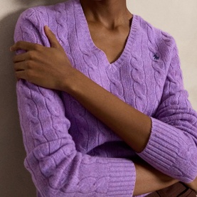 Model wearing Polo Ralph Lauren cable-knit jumper in Amethyst Falls Heather, featuring a V-neck and embroidered logo detail