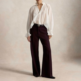 Model wearing Polo Ralph Lauren Midnight Merlot wide-leg trousers with a white draped blouse and embellished belt.