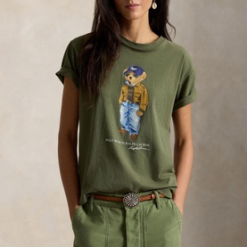 Model wearing Polo Ralph Lauren Dense Olive T-Shirt with Polo Bear graphic, paired with khaki trousers and brown belt.