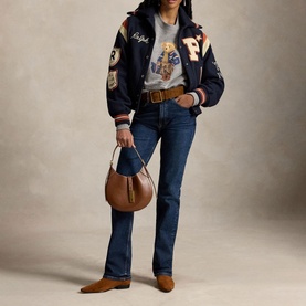 Model wearing Polo Ralph Lauren Dark Vintage Heather sweat top, styled with navy varsity jacket, dark jeans, and carrying a brown hobo bag.