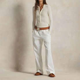 Model wearing Polo Ralph Lauren Deckwash White trousers, styled with a white ribbed top and brown belt and sandals.