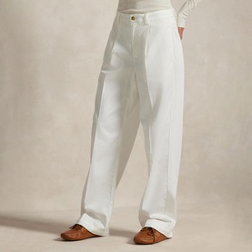 Model wearing Polo Ralph Lauren deckwash white wide-leg trousers with pleat front, styled with tan loafers and white long-sleeve top.