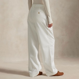 Model wearing Polo Ralph Lauren Deckwash White wide-leg trousers, rear view, styled with cream knit top and tan loafers
