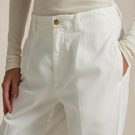 Model wearing Polo Ralph Lauren deckwash white trousers with gold-tone button detail, styled with a cream long-sleeve top.
