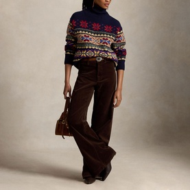 Model wearing navy Fair Isle turtleneck jumper with multicolour pattern, styled with brown wide-leg cord trousers and carrying a tan leather bag.