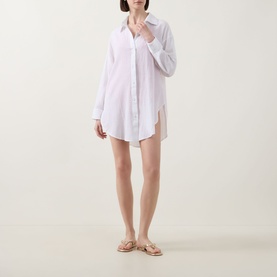 Model wearing Sea Level Vacay Cruise Shirt in white cotton, oversized fit with long sleeves, point collar and curved hem, styled with tan sandals