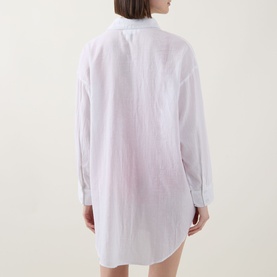 Model wearing Sea Level Vacay Cruise Shirt in white, shown from behind, featuring long sleeves, buttoned cuffs and curved hem.