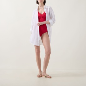 Model wearing Sea Level Vacay Cruise Shirt in white cotton over a red swimsuit, styled with beige sandals.