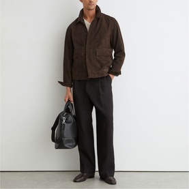 Model carrying dark brown Reiss bag, styled with brown suede jacket, black wide-leg trousers and dark leather shoes.