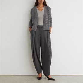 Model wearing Reiss charcoal grey relaxed tapered trousers, styled with a grey cable-knit cardigan, white vest and black heels.