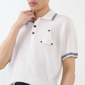 Model wearing Jacquemus white polo with navy tipping on collar and cuffs, chest pocket with button detail, short sleeves