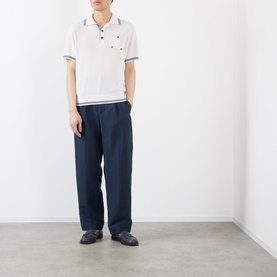 Model wearing Jacquemus white polo with navy tipped collar and cuffs, styled with wide-leg navy trousers and dark loafers