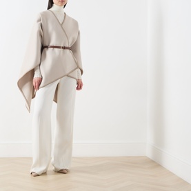 Model wearing Max Mara Accessories camel virgin wool cape, styled with brown leather belt, white wide-leg trousers and beige heeled mules.