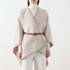 Model wearing Max Mara Accessories camel virgin wool cape with whipstitch trim and brown leather belt, styled with white roll-neck and trousers