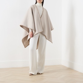 Model wearing Max Mara Accessories camel virgin wool cape over white turtleneck and wide-leg trousers with flat mules.