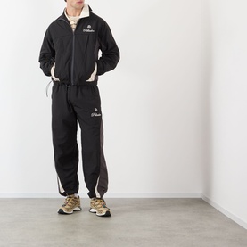 Model wearing Pellador OG Logo Track Jacket in black with matching track pants, contrast panels, and gold trainers.