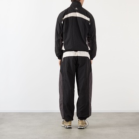 Model wearing Pellador OG Logo Track Jacket in black with contrast panels, styled with matching black track pants and trainers. Rear view.