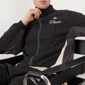 Model wearing Pellador OG Logo Track Jacket in black with contrast panels, funnel neck, zip fastening, styled with matching black track pants.