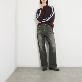 Model wearing Pellador Overlap Cable Knit Sweater in brown with light blue stripe detail, styled with dark wash wide-leg jeans and black boots.