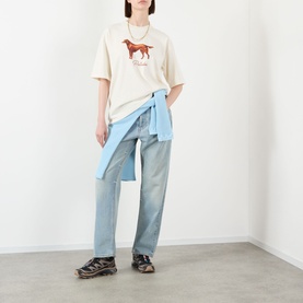 Model wearing Pellador Red Setter Logo T-Shirt in white with light blue jeans and a blue shirt tied at the waist.