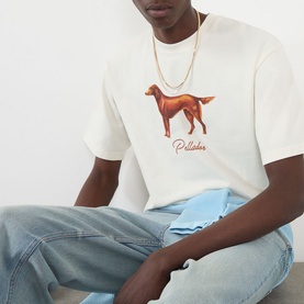 Model wearing Pellador Red Setter Logo T-Shirt in white with dog graphic print, styled with light wash jeans and gold chain necklace.