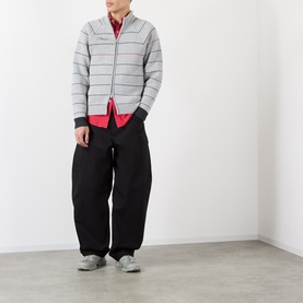 Model wearing Pellador grey striped cotton zip-through knit, styled with a red top and black wide-leg trousers