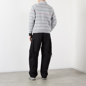 Model wearing Pellador grey striped cotton zip through knit, styled with black cargo trousers and grey trainers, seen from behind.