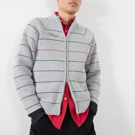 Model wearing Pellador grey striped cotton zip-through knit, styled with a red shirt and dark trousers