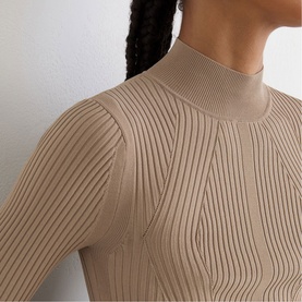 Model wearing Reiss beige ribbed knit top with mock neck and long sleeves, close-up detail shot