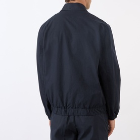 Model wearing A.P.C. dark navy cotton casual jacket, rear view showing elasticated hem and ribbed cuffs, styled with navy trousers.