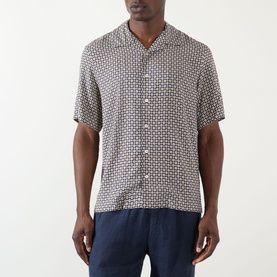 Model wearing A.P.C. Bennet Printed Shirt in dark navy geometric print, camp collar, short sleeves, styled with navy trousers.