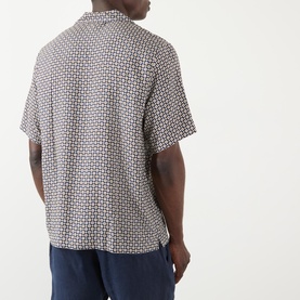Model wearing A.P.C. Bennet Printed Shirt in dark navy, short sleeves, camp collar, geometric print, back view, styled with navy trousers