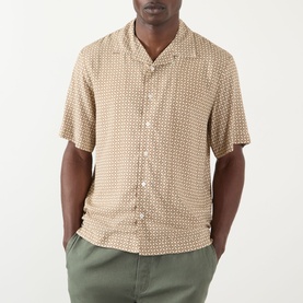 Model wearing A.P.C. beige viscose casual shirt with geometric print, short sleeves and camp collar, styled with olive green trousers