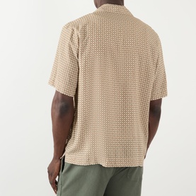 Model wearing A.P.C. beige geometric print short-sleeve shirt, back view, styled with olive green trousers.