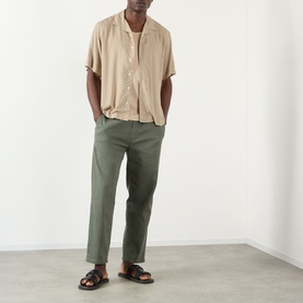 Model wearing A.P.C. beige short-sleeve viscose casual shirt, styled with olive green trousers and black sandals.